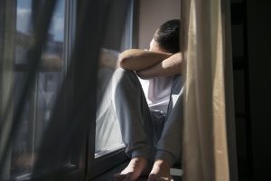 Man sitting by a window with soft shadows, reflecting quietly