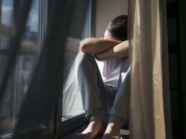 Man sitting by a window with soft shadows, reflecting quietly
